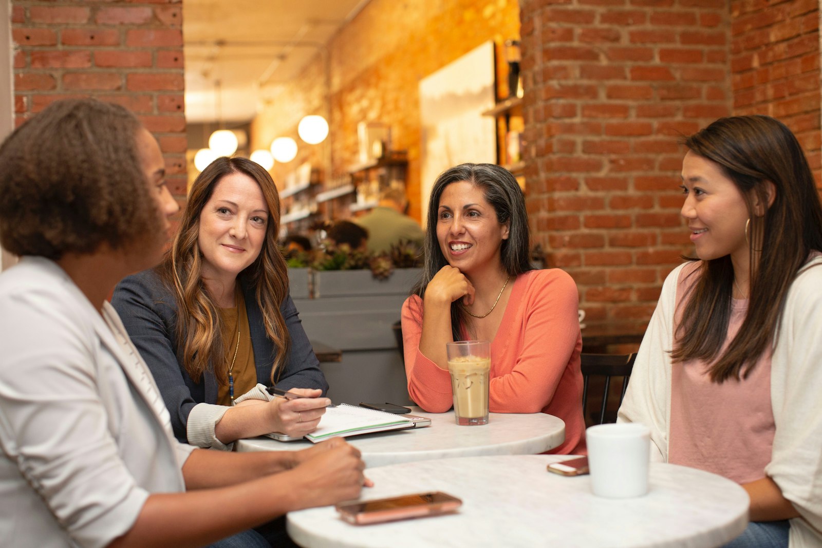 Four women talking and laughing around a cafe table